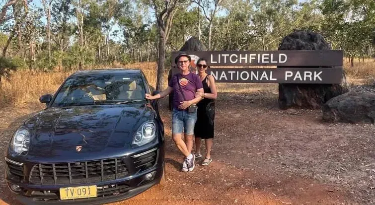 Couple Posing Next to a Black Porsche Suv — Litchfield VIP Tours In Darwin City, NT
