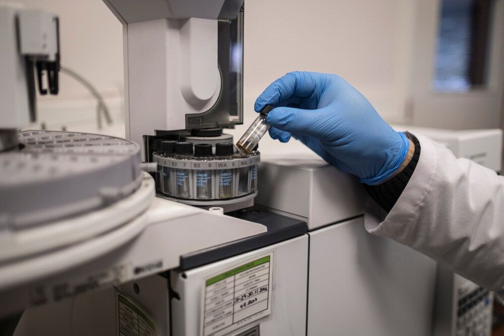 A Person Wearing Blue Gloves Is Using A Machine In A Laboratory — Australian Asbestos Management Pty Ltd In Kunda Park, QLD