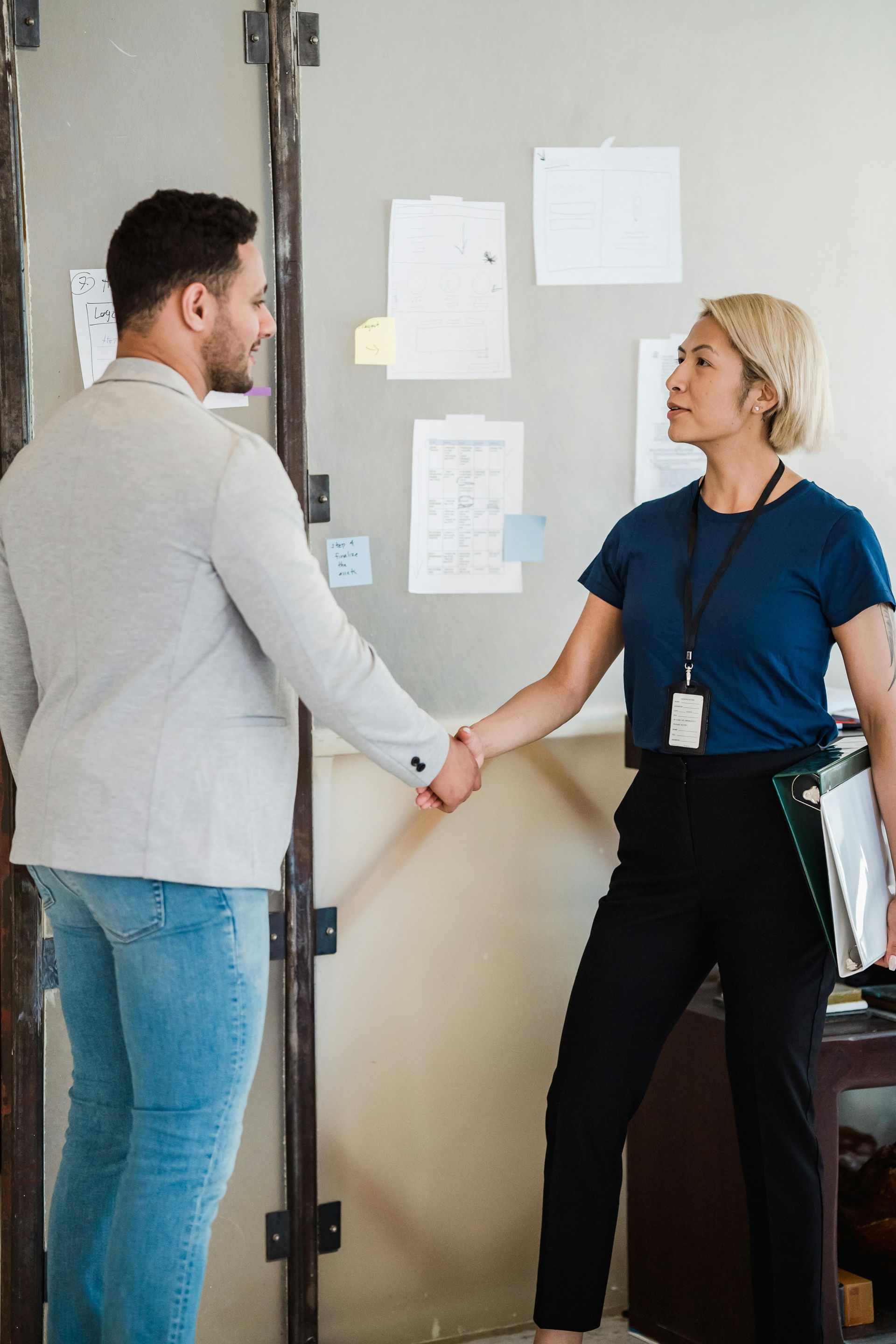 A Man And A Woman Are Shaking Hands In An Office — Australian Asbestos Management Pty Ltd In Kunda Park, QLD