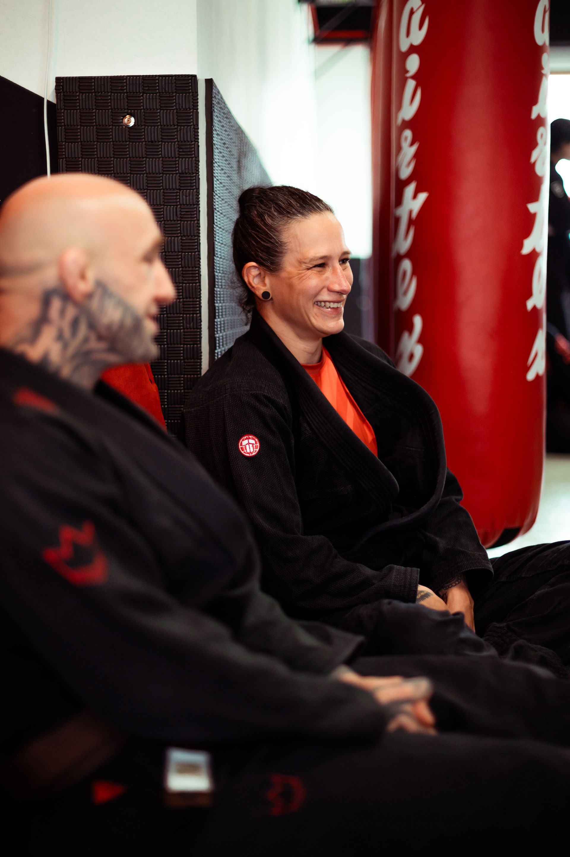 Zwei Personen üben brasilianisches Jiu-Jitsu auf einer Matte. Eine Person im pinkfarbenen Gi hält die andere im schwarzen Gi fest; beide befinden sich am Boden.