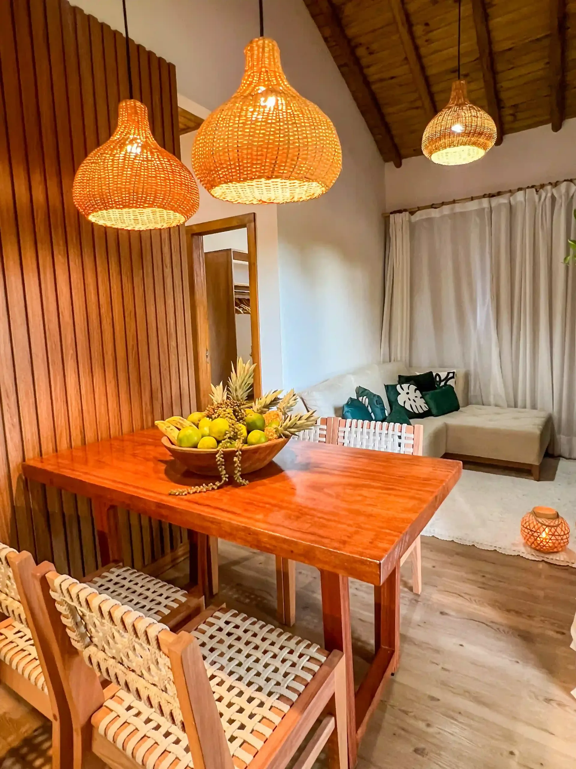 Uma sala de jantar com uma mesa e cadeiras de madeira e uma tigela de frutas sobre ela - pousada-recanto-caxandó