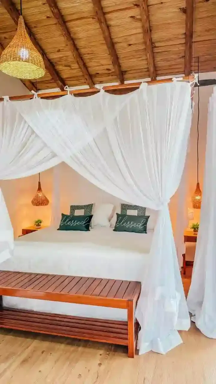 Um quarto com uma cama de dossel e um banco de madeira - pousada-recanto-caxando