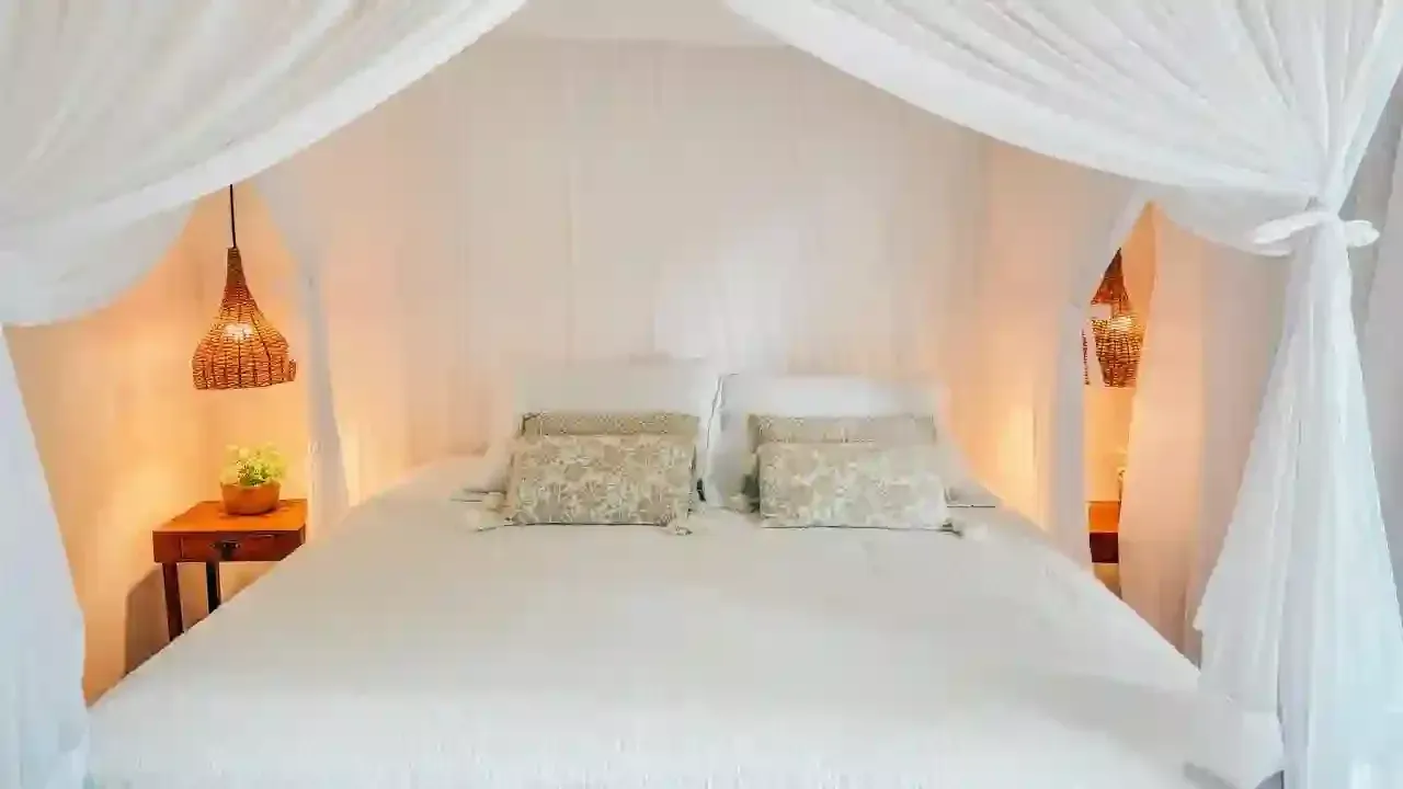 Um quarto com uma cama de dossel e cortinas brancas - pousada-recanto-caxando