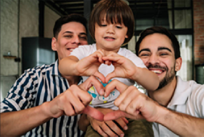 Two men and a child making a heart shape with their hands, smiling.