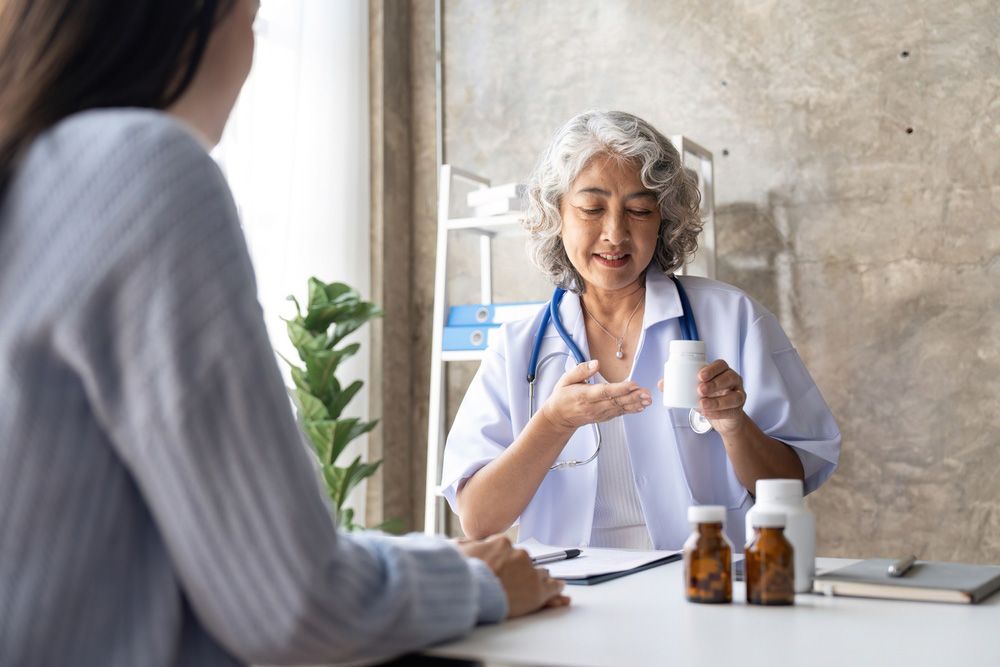 Senior Doctor Woman Holding A Pill Bottle While Talking With A Patient And Reviewing His Medication — Home Medication Reviews in Wulguru, QLD