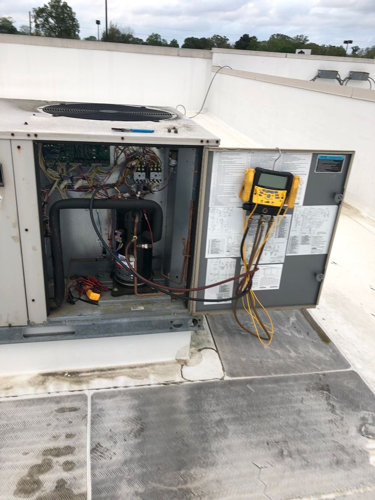 An air conditioner is being repaired on the roof of a building.