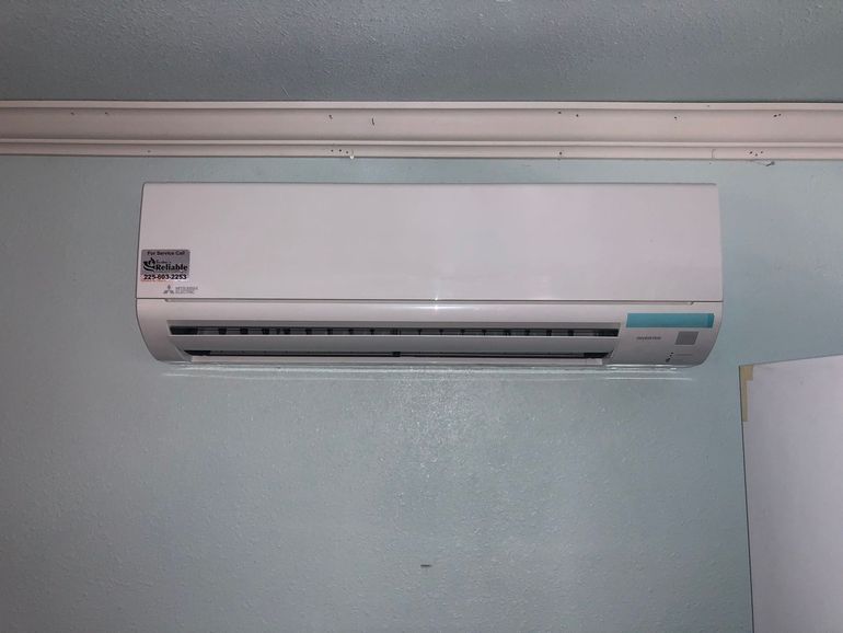 A white air conditioner is hanging on a wall in a room.