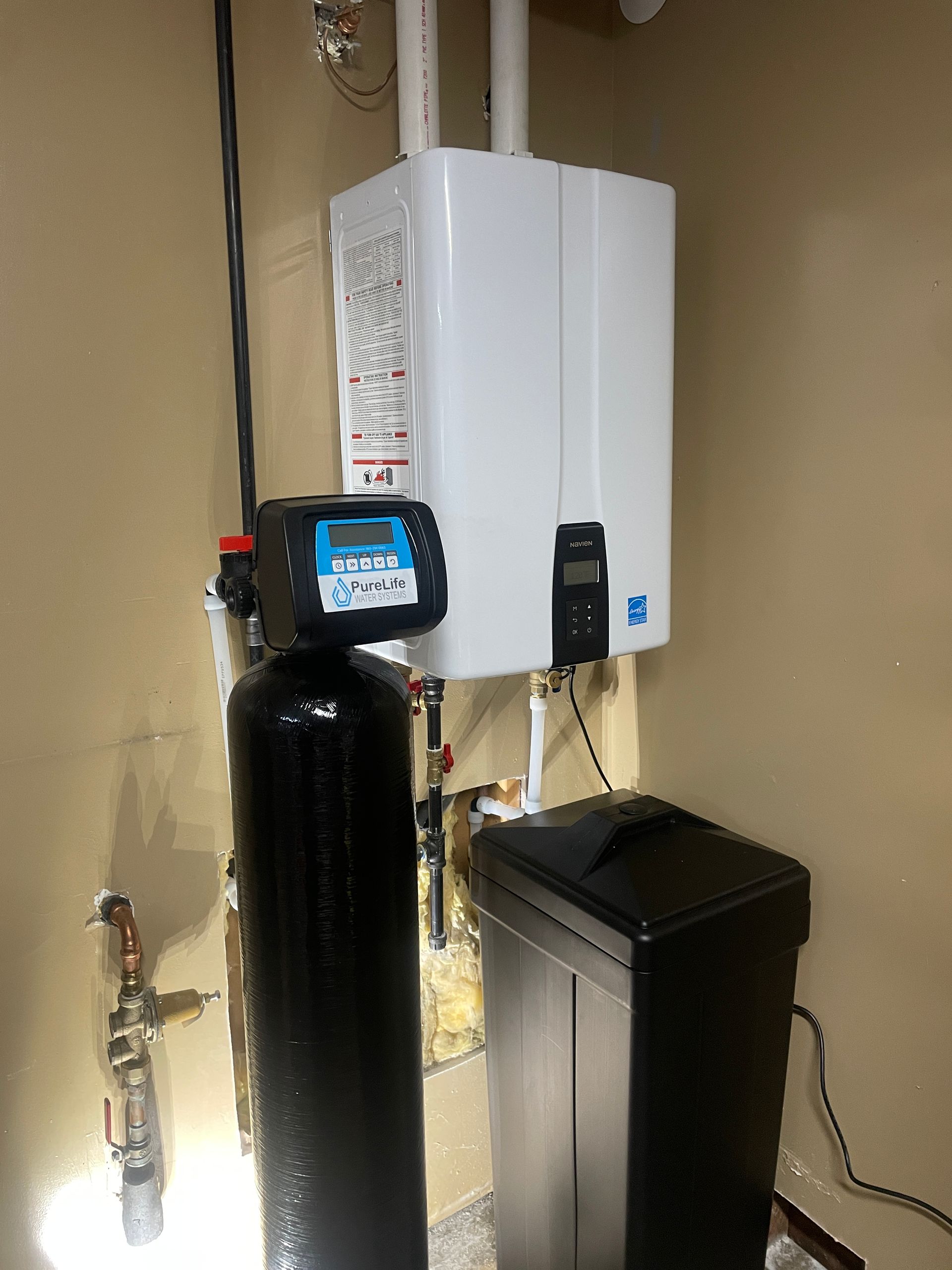 A water filter is sitting next to a boiler in a room.