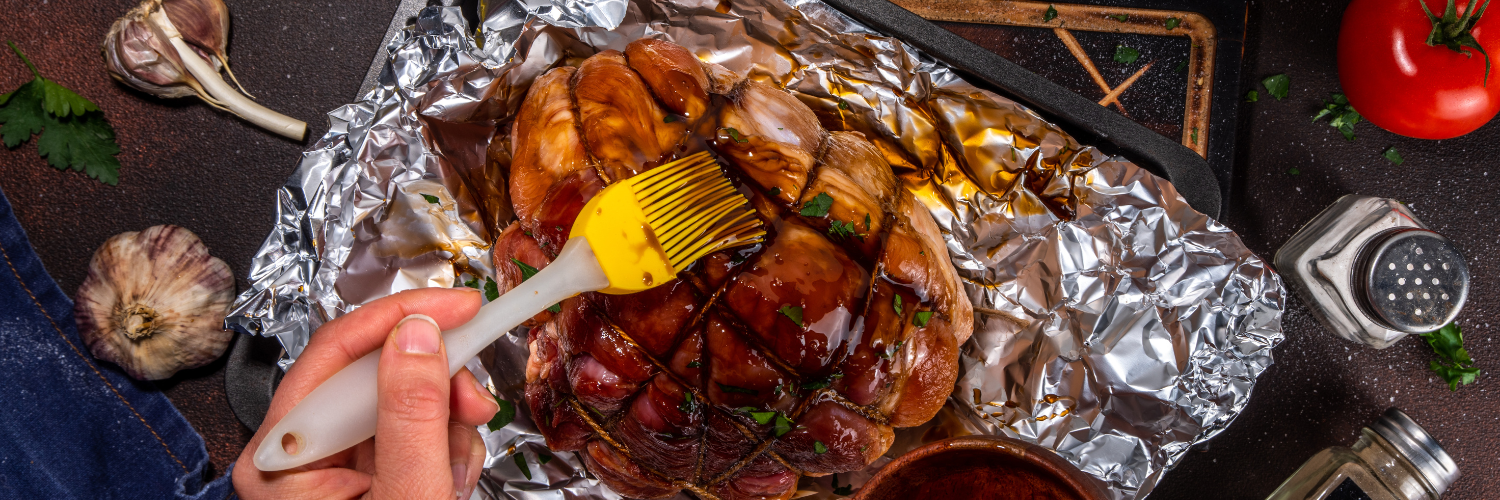 A person is spreading Freakshow Savory Asian Teriyaki sauce onto a pork butt