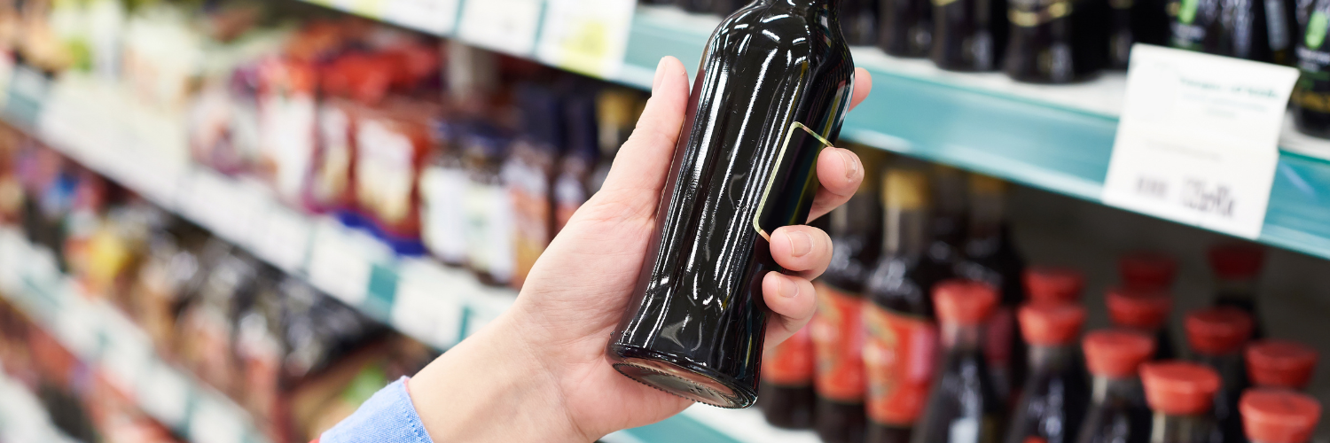 A person is holding a bottle of soy sauce in a store.