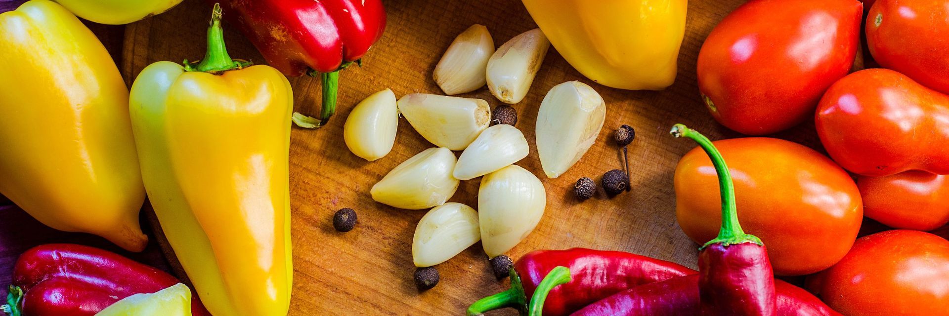 There are many different types of peppers and tomatoes on the table.