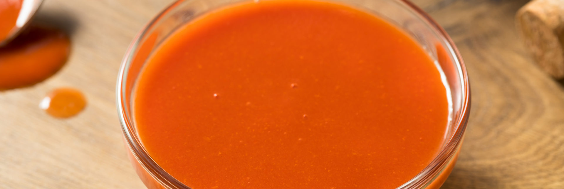 A close up of a container of hot sauce on a wooden table.