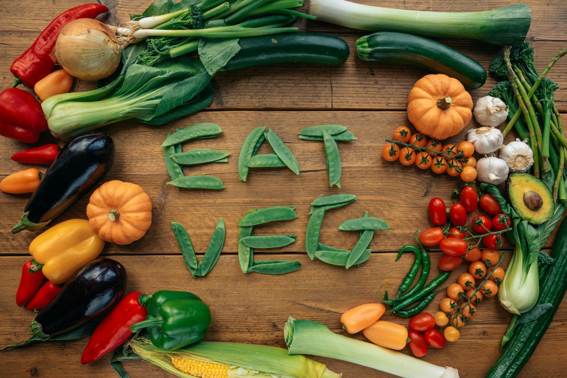 A wooden table topped with vegetables and the words `` eat veg '' written in green letters.