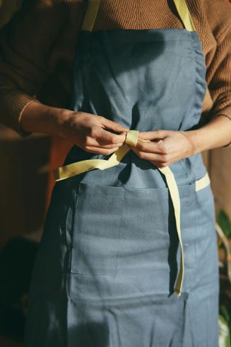 A woman wearing a blue apron with a yellow ribbon around her waist A woman wearing a blue apron with a yellow ribbon around her waist