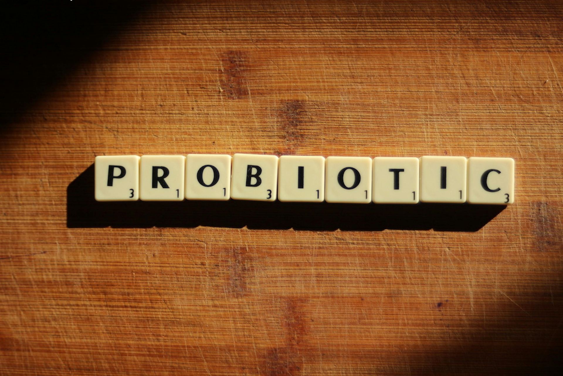 The word probiotic is written in scrabble tiles on a wooden table.