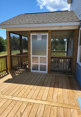 Screened porch on a wooden deck. The porch has a door and screens. Blue house on the right.