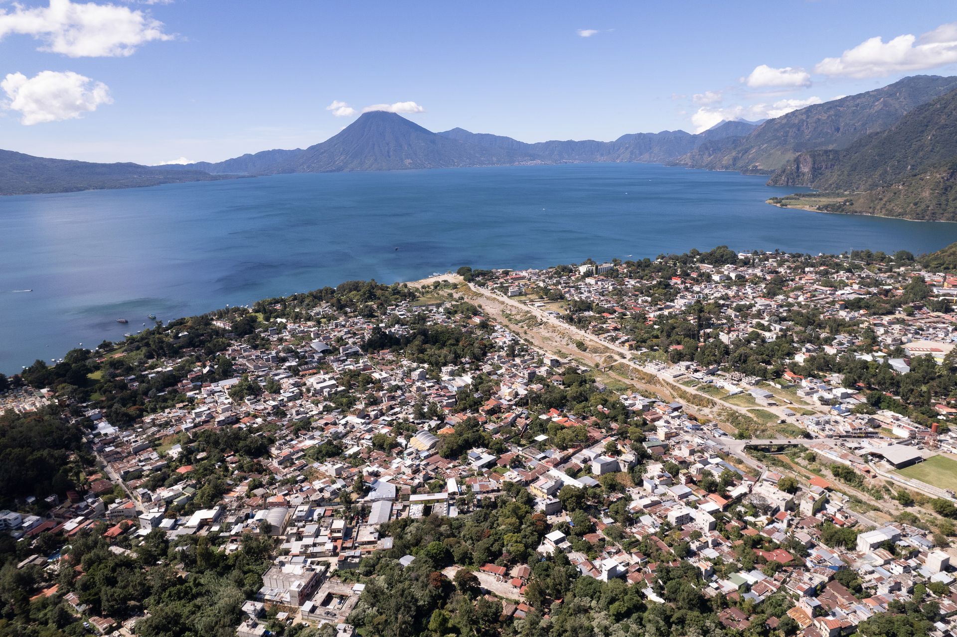 An aerial view of a city next to a lake with mountains in the background.