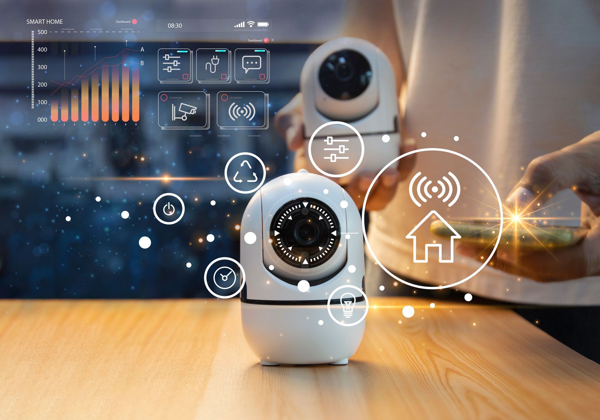 A person is holding two security cameras on a wooden table.