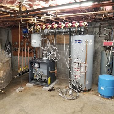 A basement with a water heater and a boiler.
