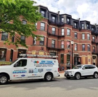 A white van is parked in front of a brick building.