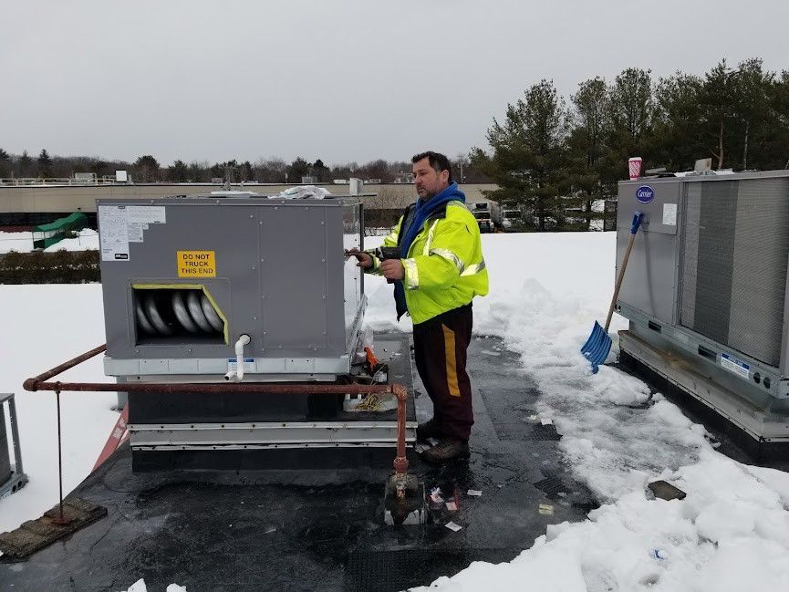 A man in a yellow jacket is working on an air conditioner