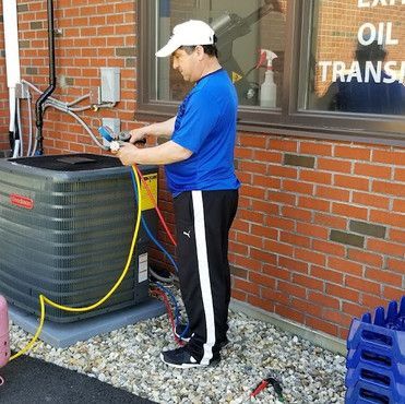 A man is working on an air conditioner outside of a brick building.