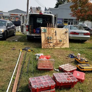 A van filled with tools is parked in a grassy field.