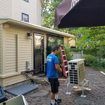 A man is standing in front of a house with a ladder.