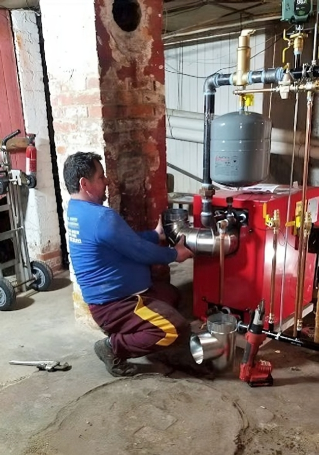 A man is working on a boiler in a basement.