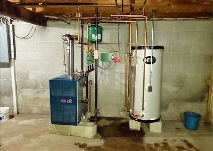 A blue boiler and a white water heater are in a basement.