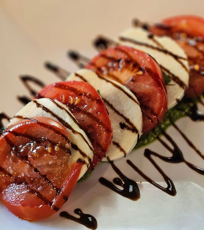 A white plate topped with sliced tomatoes and mozzarella