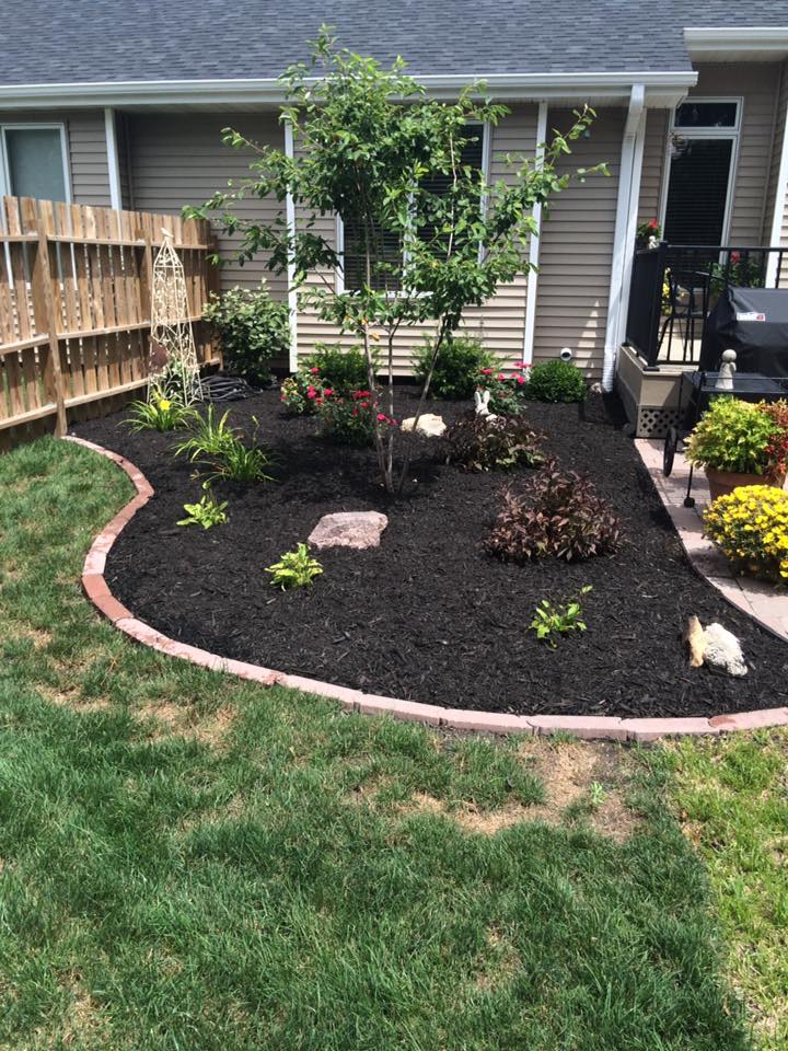 Fresh mulch being installed in residential flower bed by CD’s Lawn Care