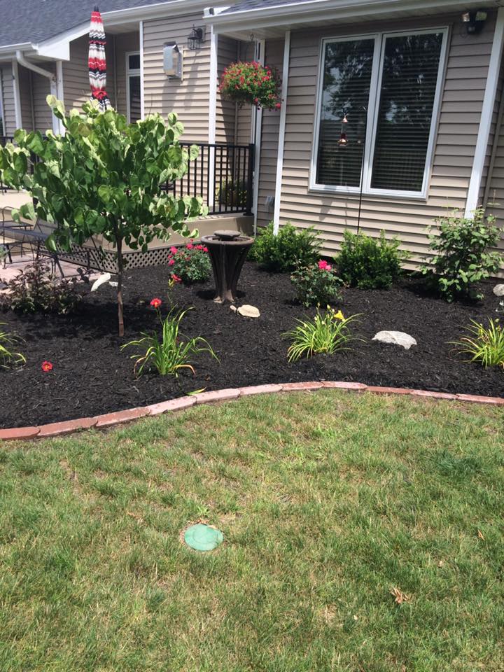 Fresh mulch being installed in residential flower bed by CD’s Lawn Care