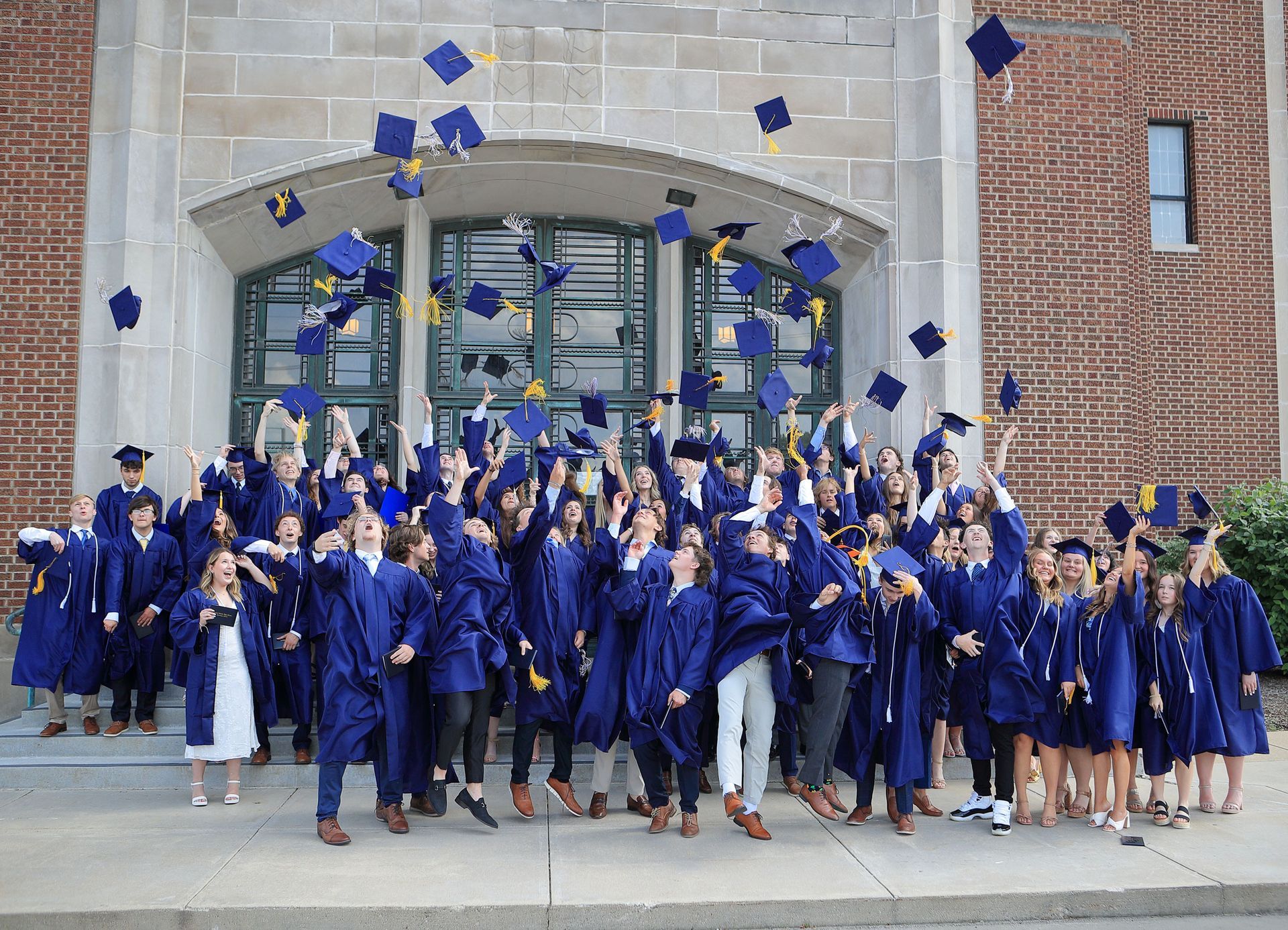 A large group of graduates are throwing their caps in the air.
