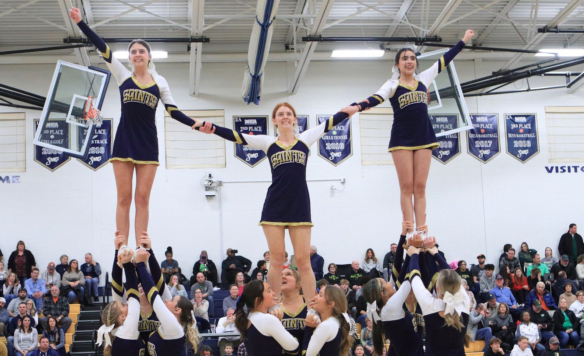 A group of cheerleaders are performing a stunt in a gym.
