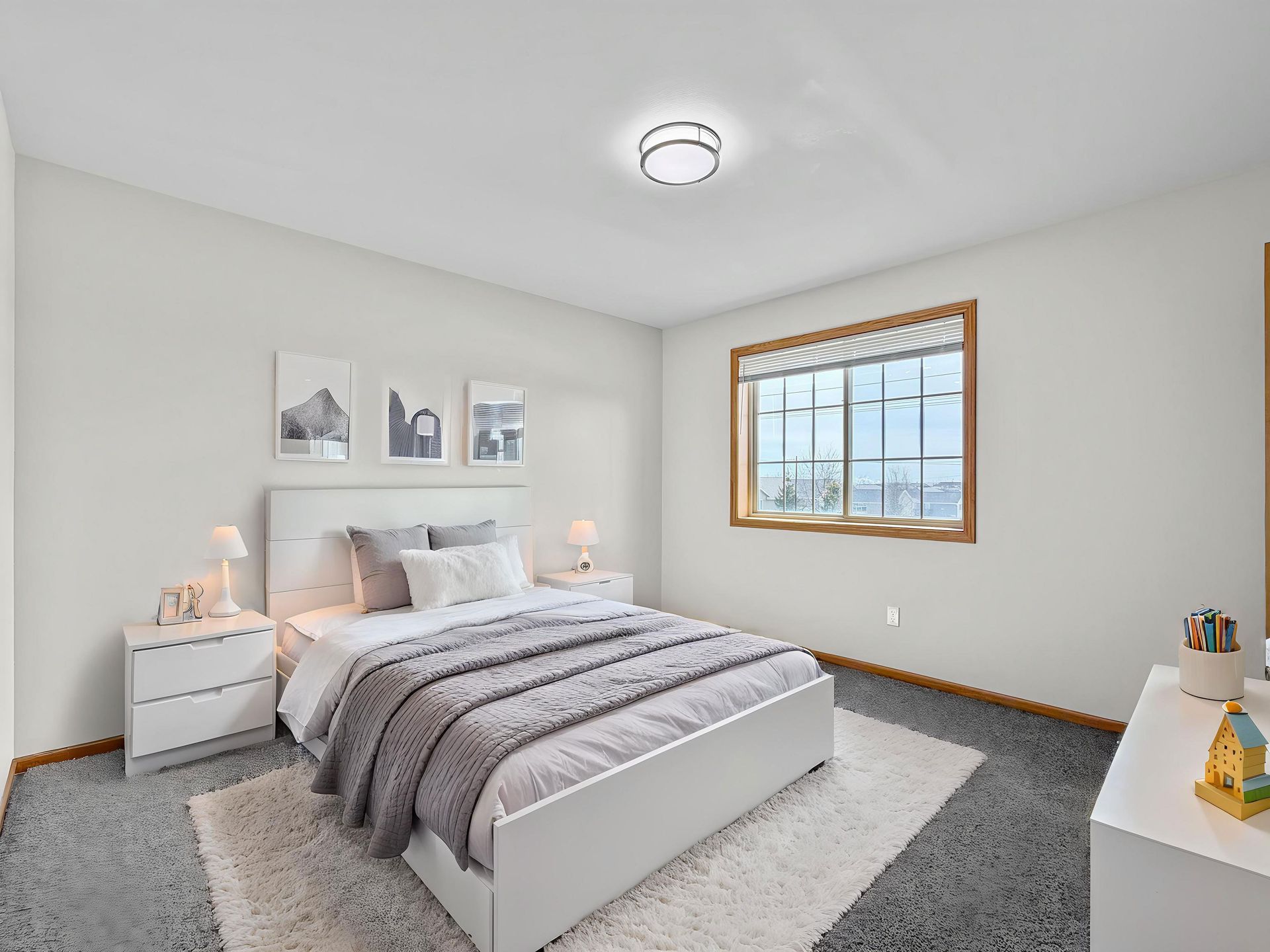 Bright living room with white sectional sofa, dresser, floor lamp, and window coverings.