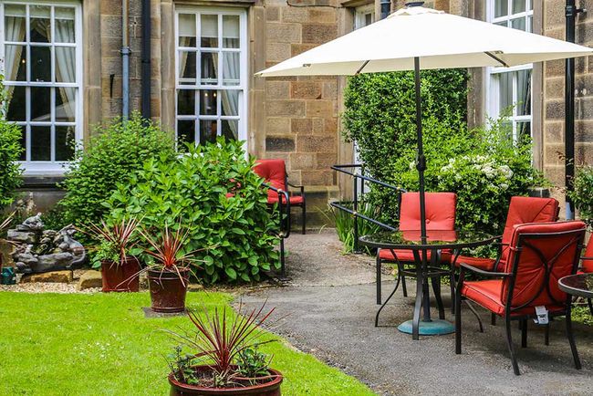 Seating area in the landscaped garden at Nunthorpe Hall with tables, chairs and parasol