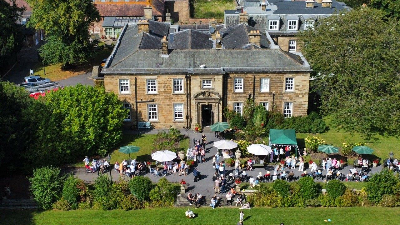Aerial view of Nunthorpe Hall during the summer fête with residents, families and outdoor stalls