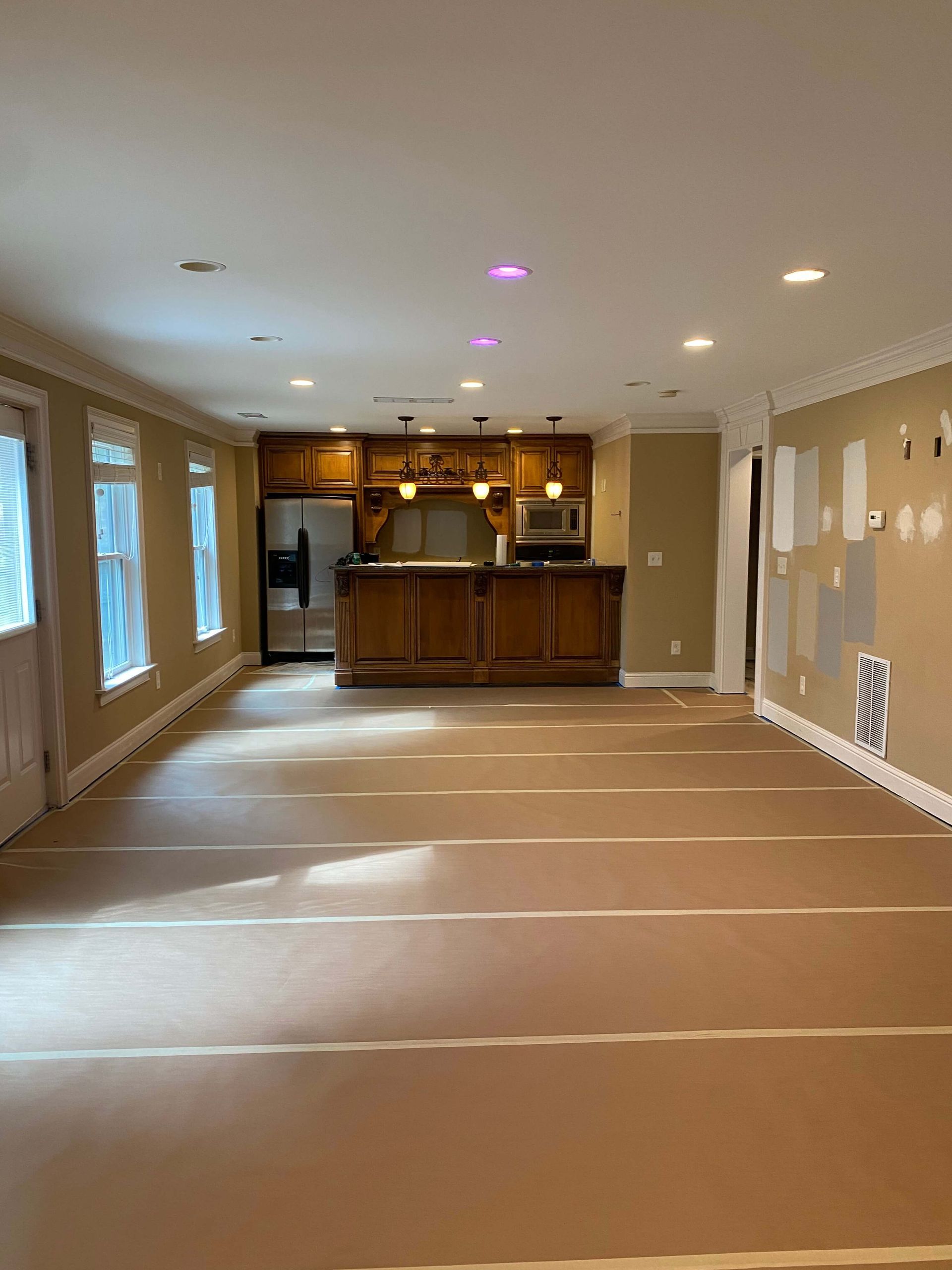 Interior room with floors covered and walls prepped for painting, showing professional preparation before painting begins.