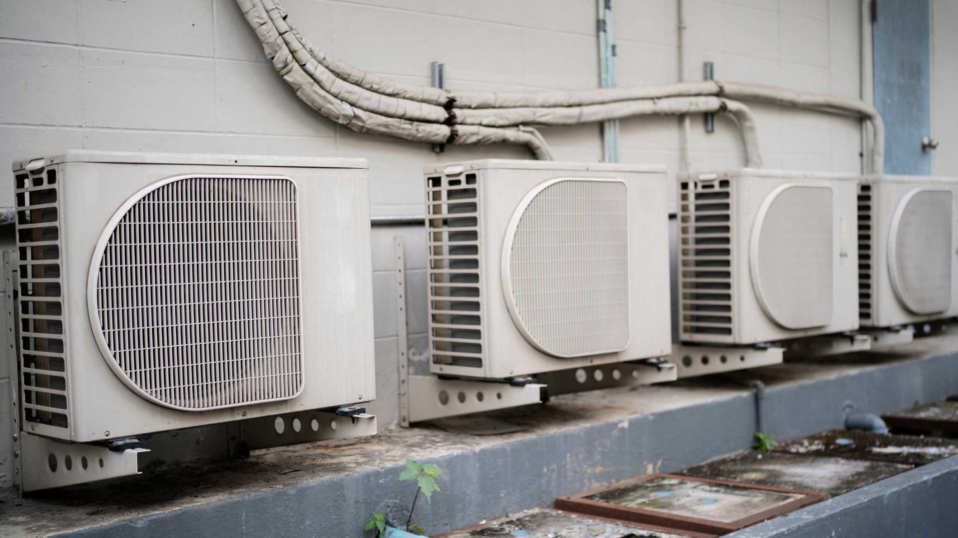 A row of air conditioners are sitting on the side of a building.