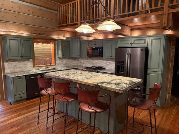 A kitchen in a log cabin with a large island and stools.