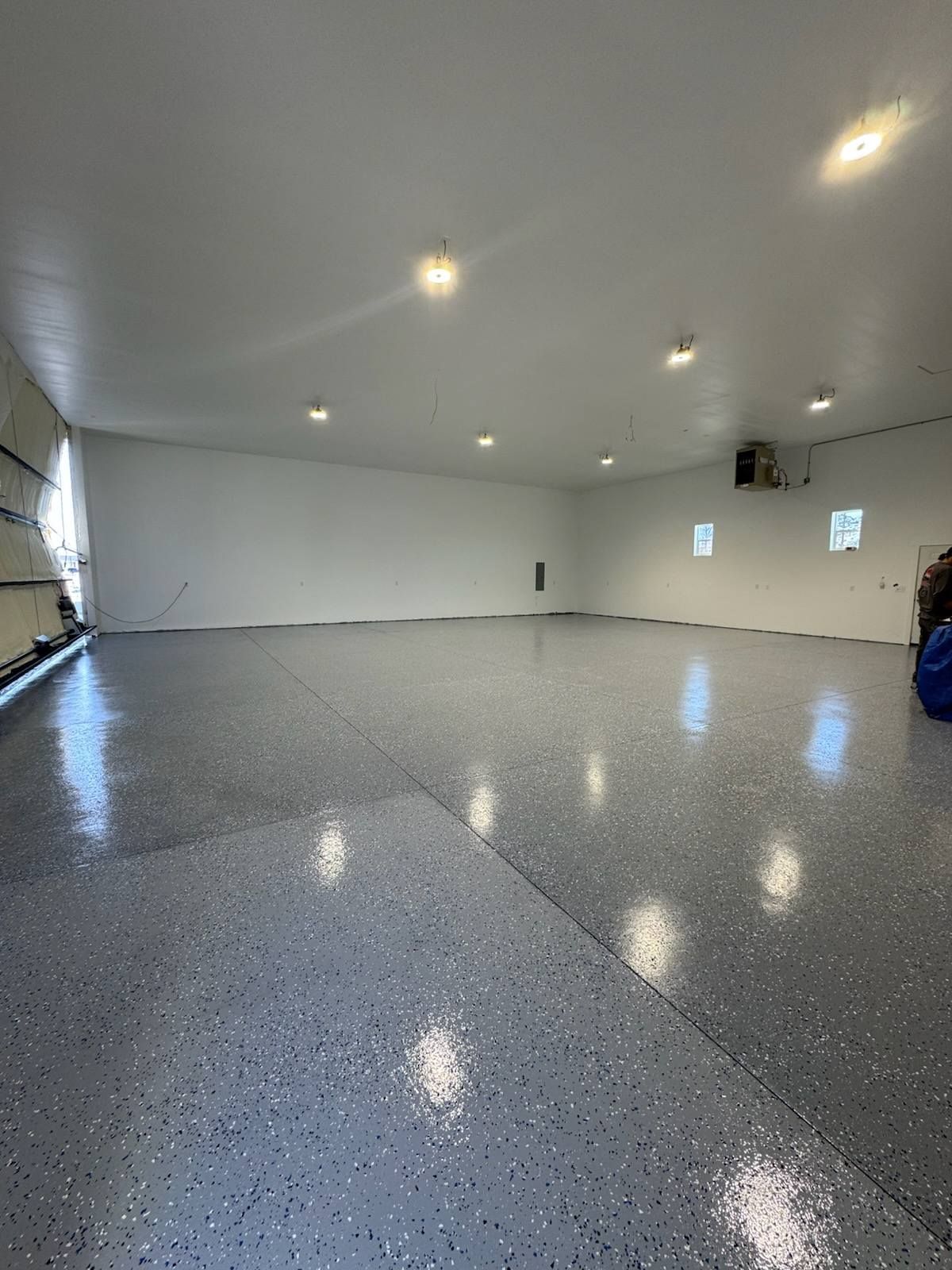 A large empty garage with a gray floor and white walls.