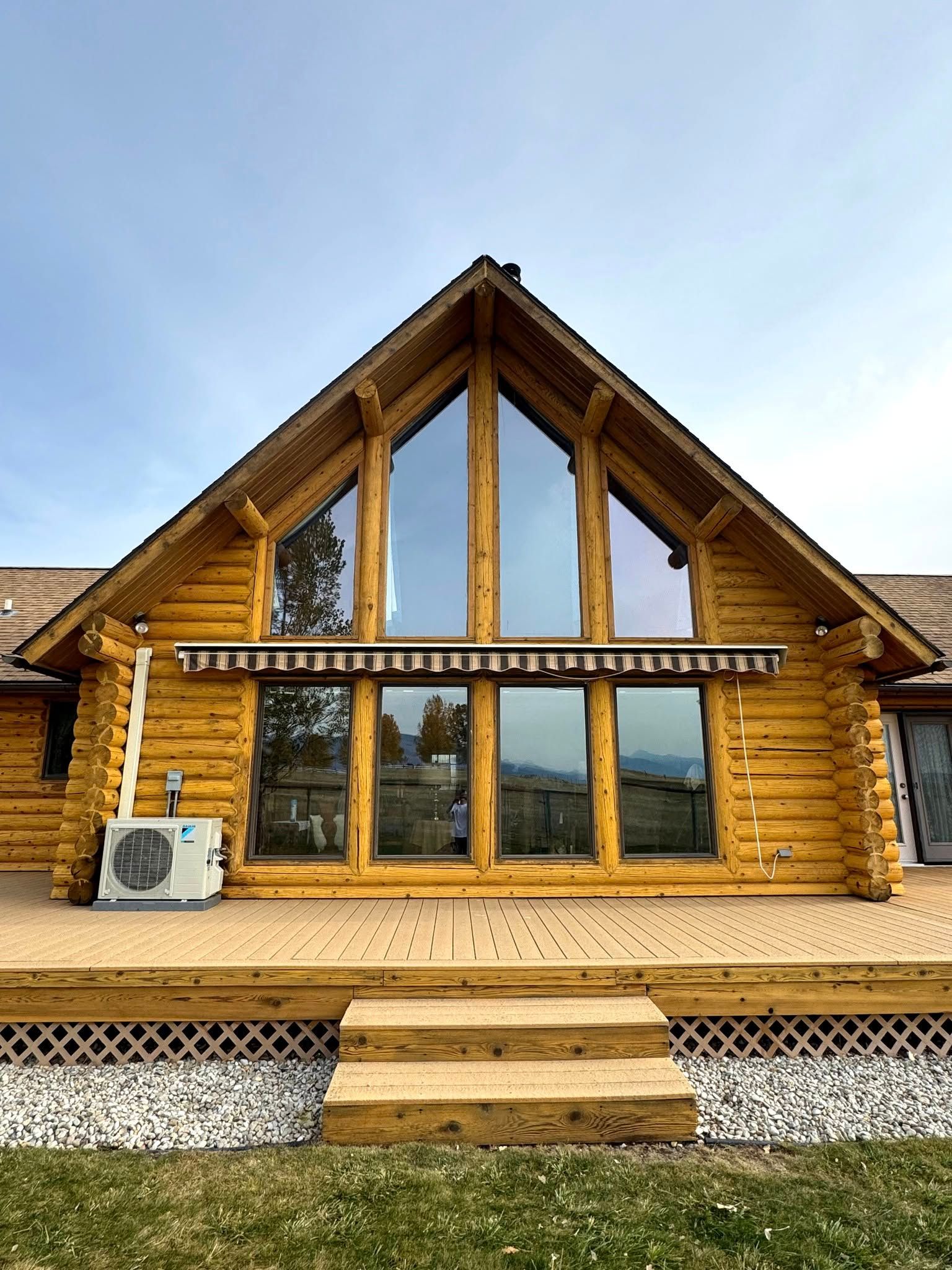 A large log cabin with a lot of windows and a deck.