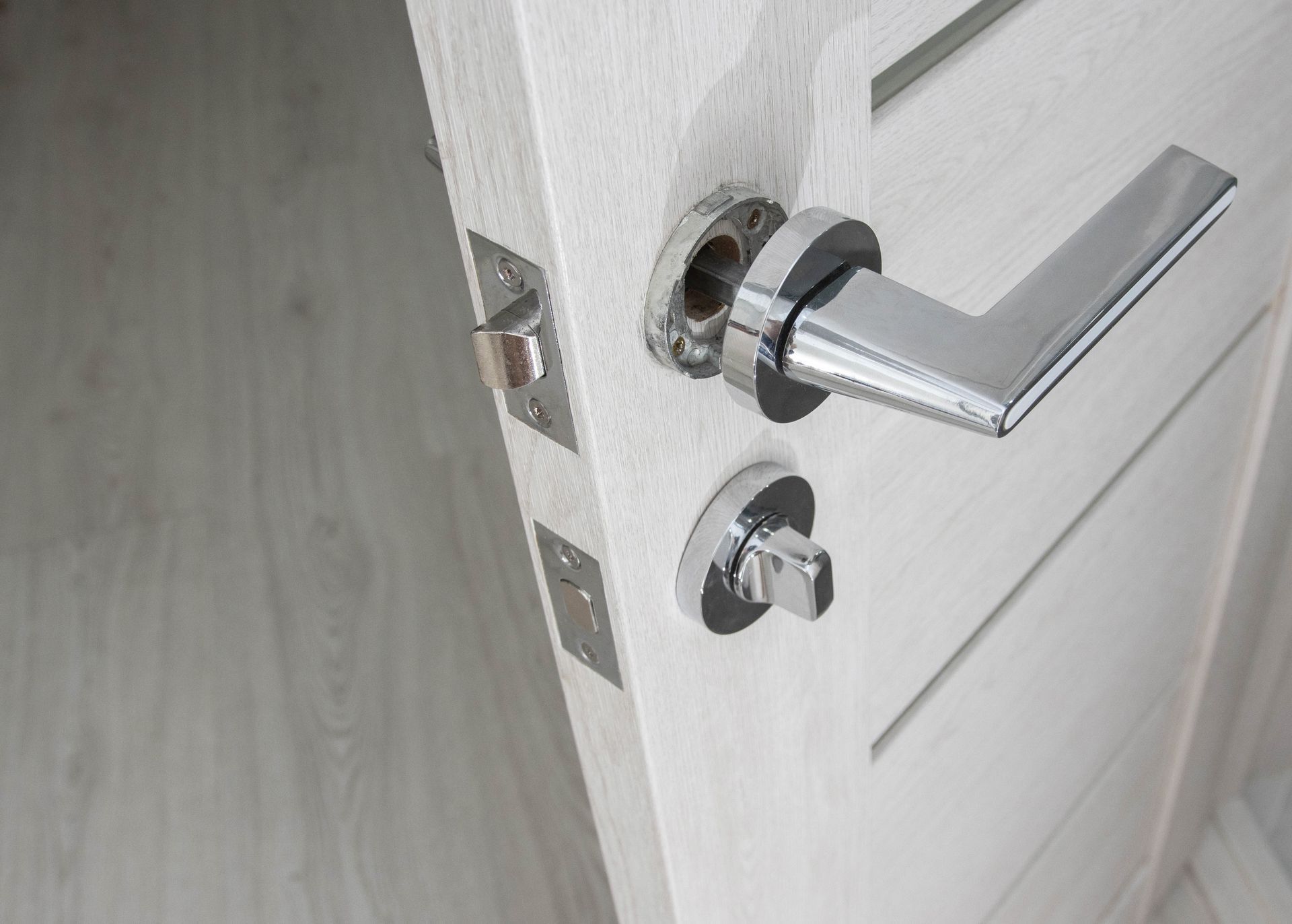 A close up of a door handle on a white door.