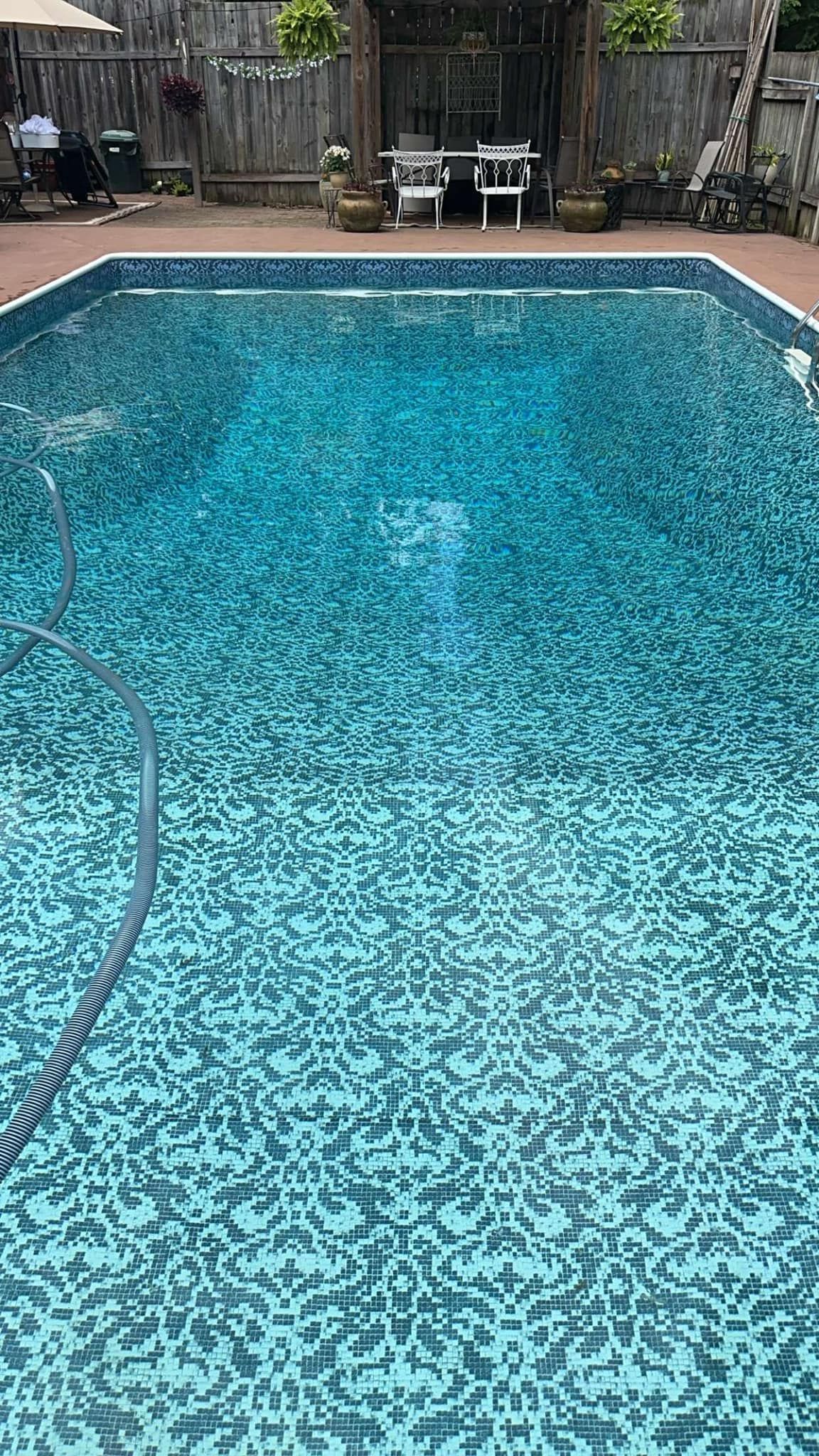 A large swimming pool filled with blue water in a backyard.
