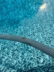 A vacuum hose is being used to clean a swimming pool.