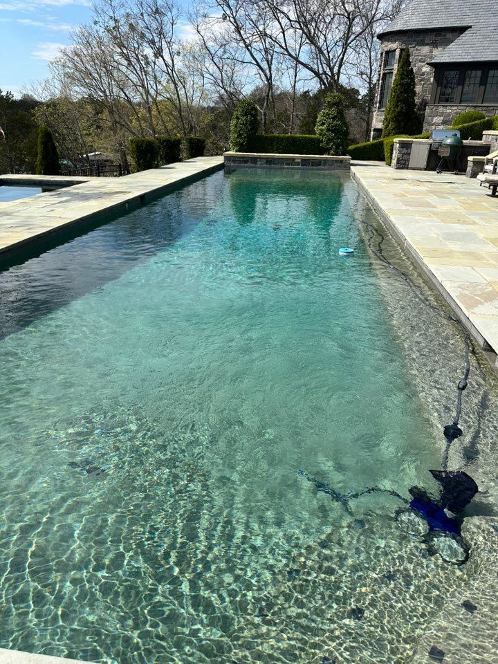 A large swimming pool with a house in the background.