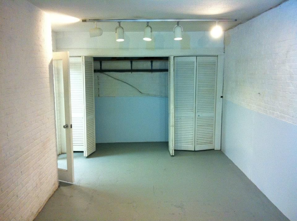 Empty room with closet and white walls, gray floor, overhead lighting.