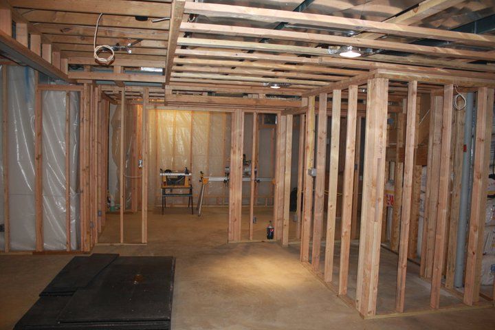 Basement with wood framing for new walls, ceiling, and concrete floor.