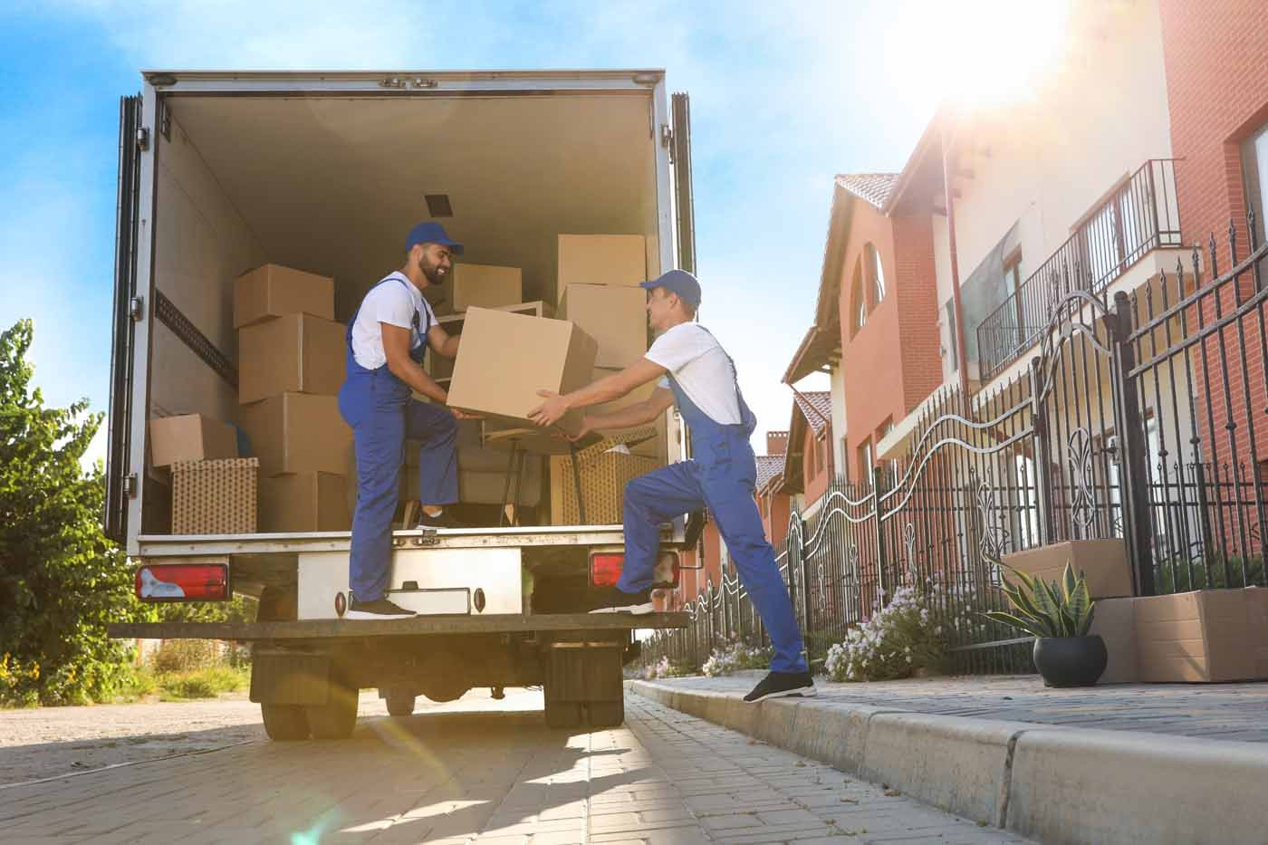 Two men are loading boxes into a moving truck.